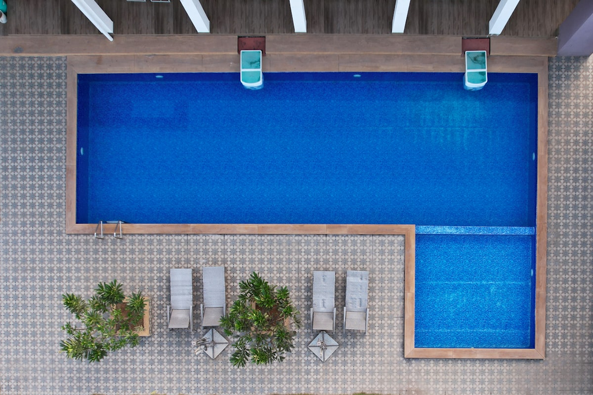 A clean L-shaped pool with loungers and planting, seen from directly above