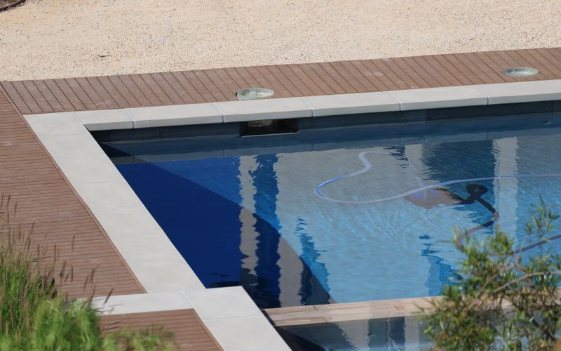 An automatic cleaner working across the floor of a clean modern pool